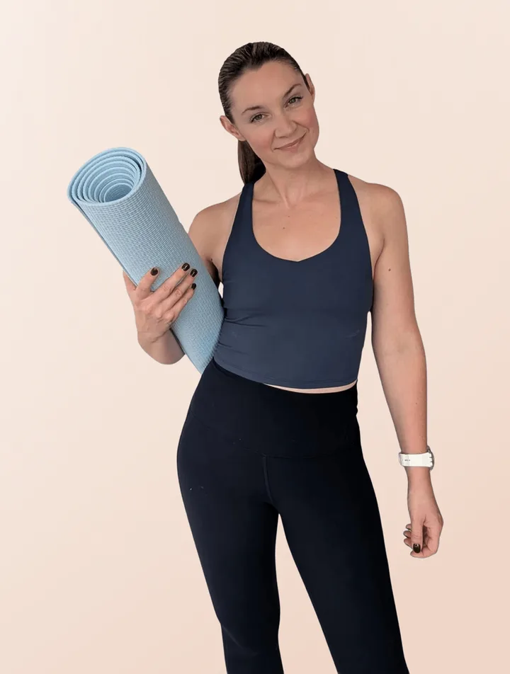 Alison Bates, founder and instructor at Root & Reach Pilates, holding a rolled mat